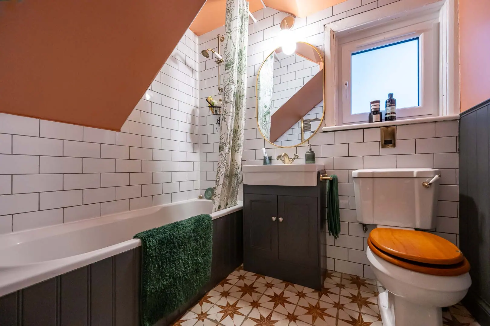 Bathroom under the eaves, with metro tiling and a patterned floor.