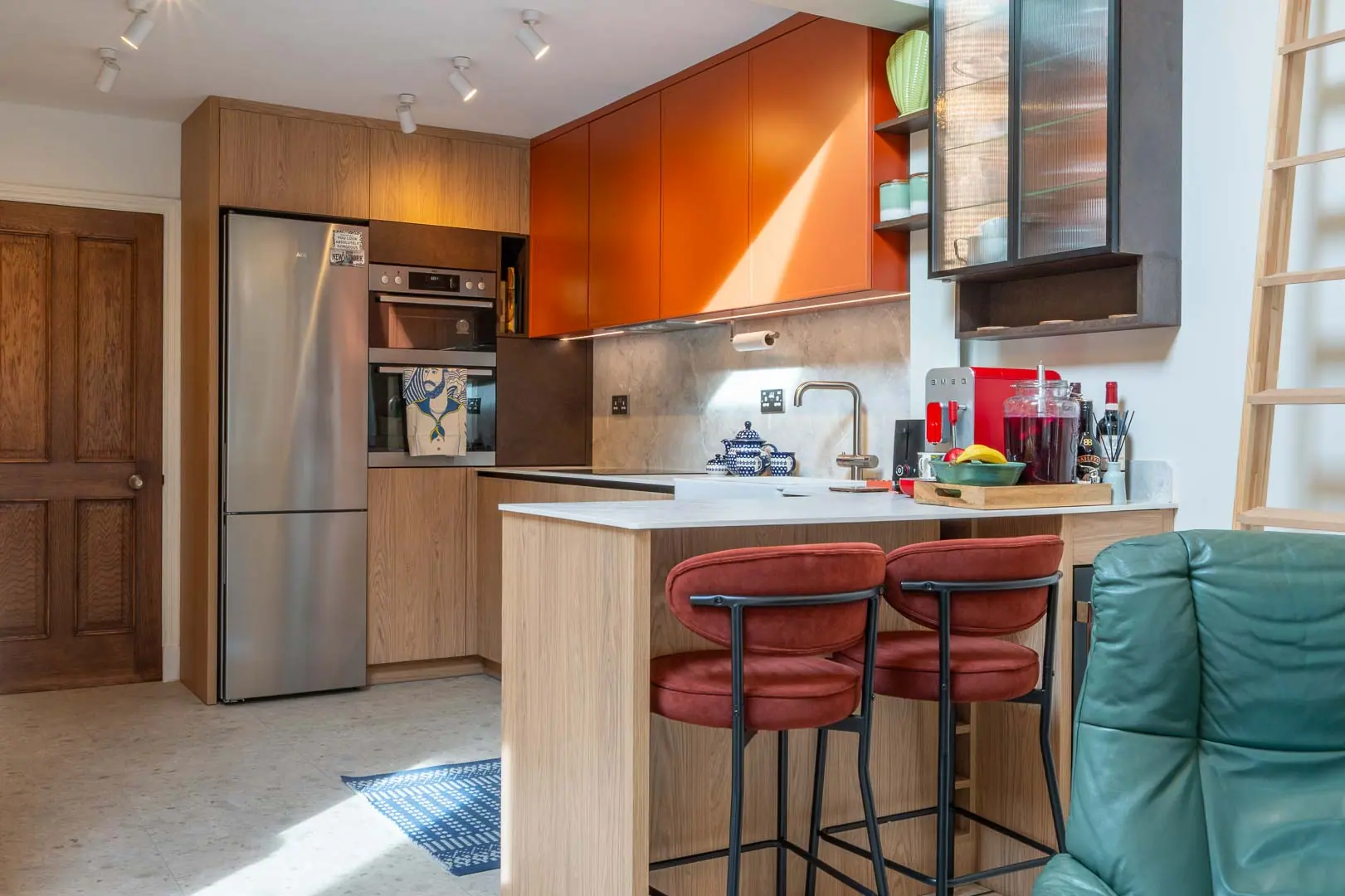 Bespoke kitchen in oak and burnt orange, with stools pulled up to the island.