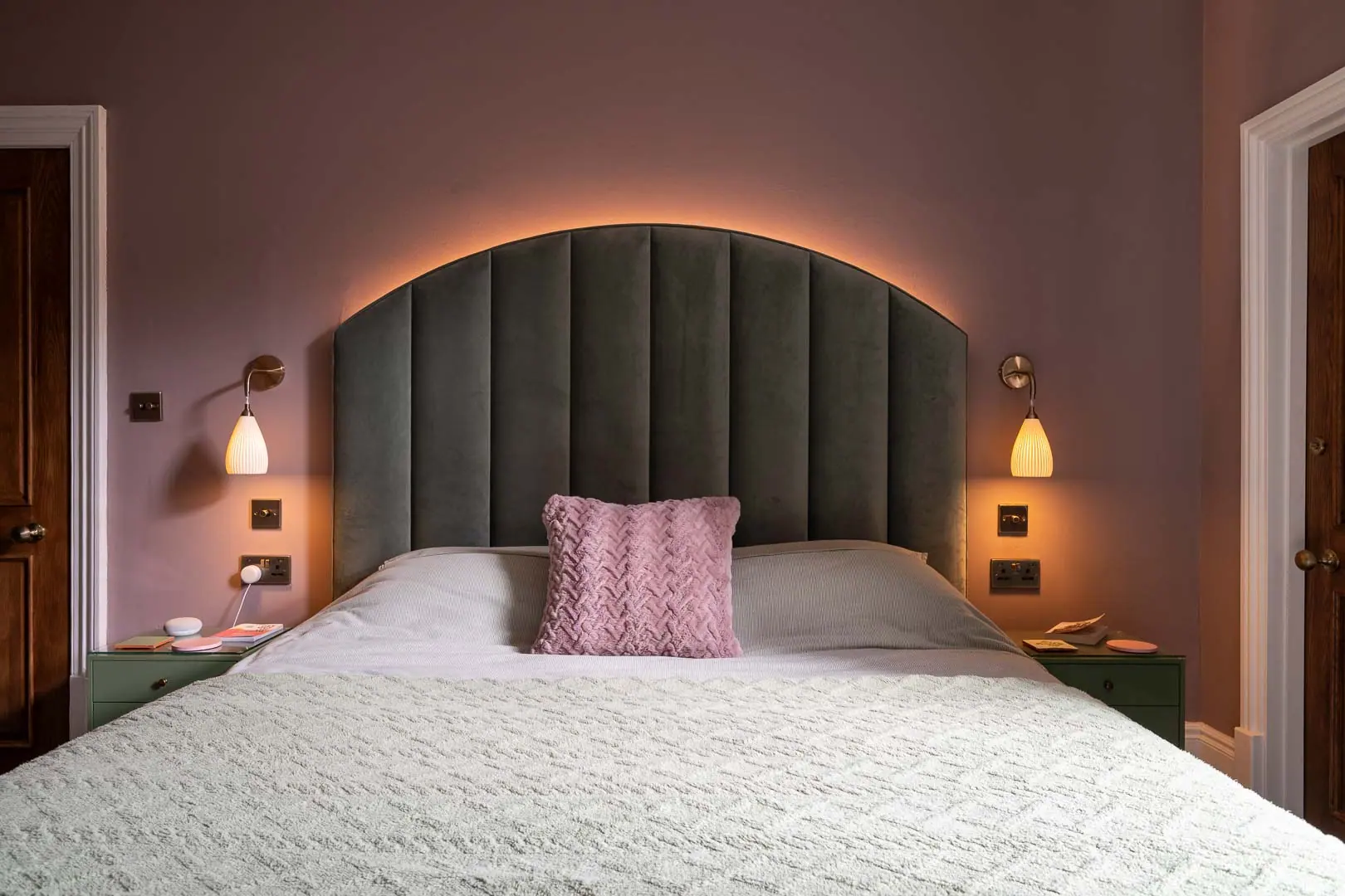 An arched, upholstered headboard made to fit the bedroom wall.