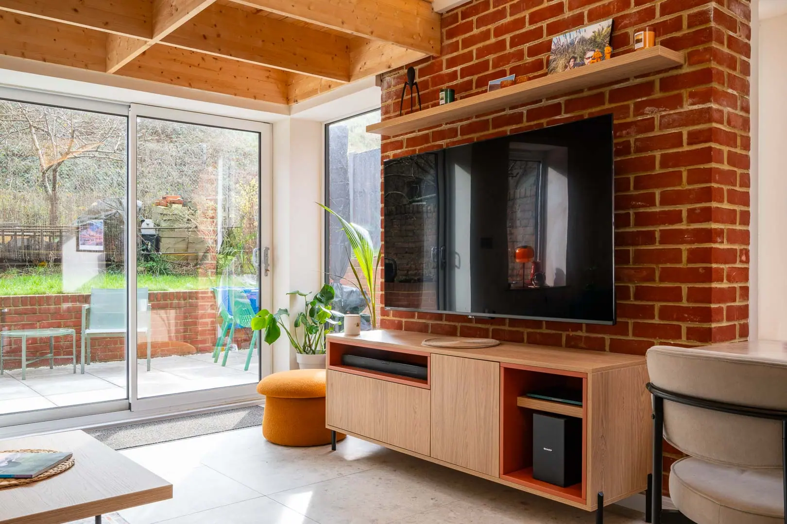 Exposed brick behind the media wall, with oak joinery built to the same line.